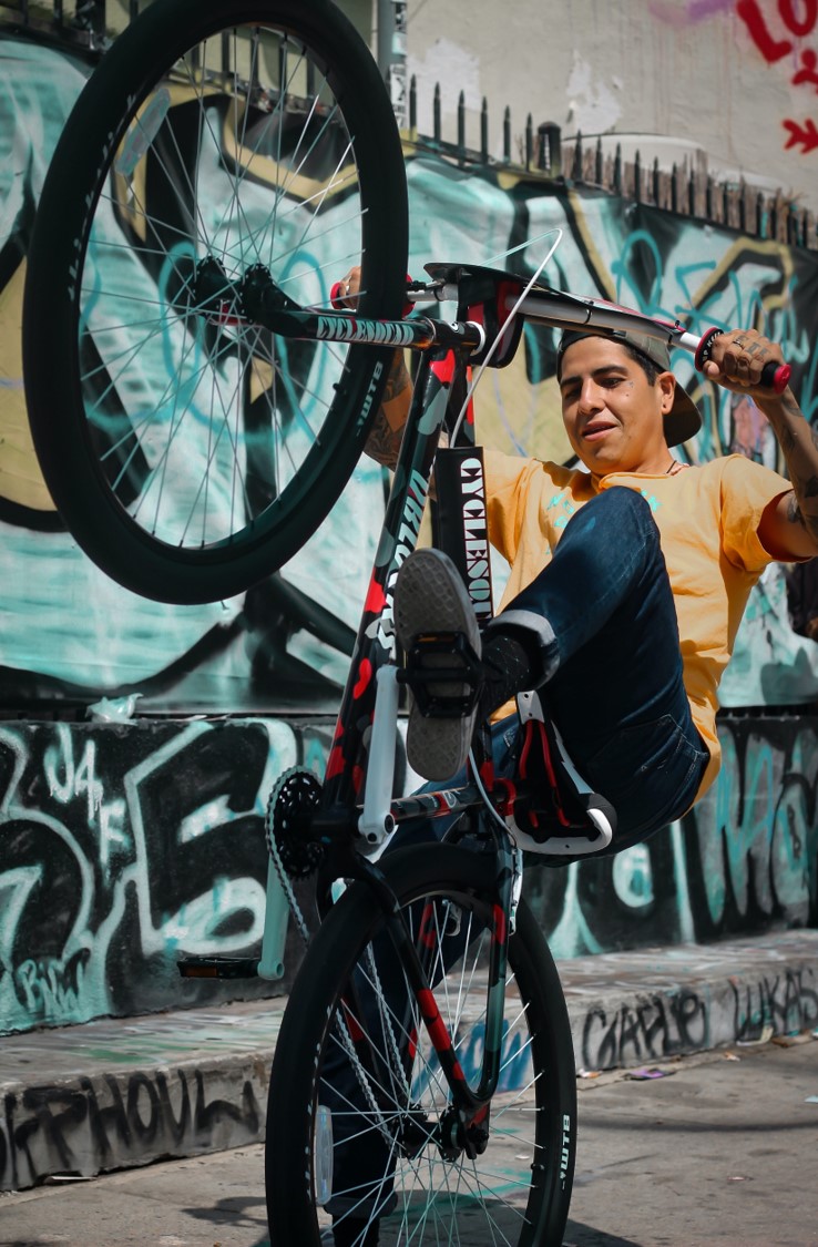 A young man is doing a wheelie on a bicycle.