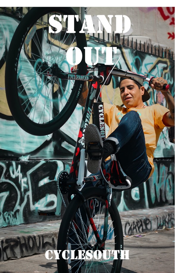 A young man is doing a wheelie on a bicycle.